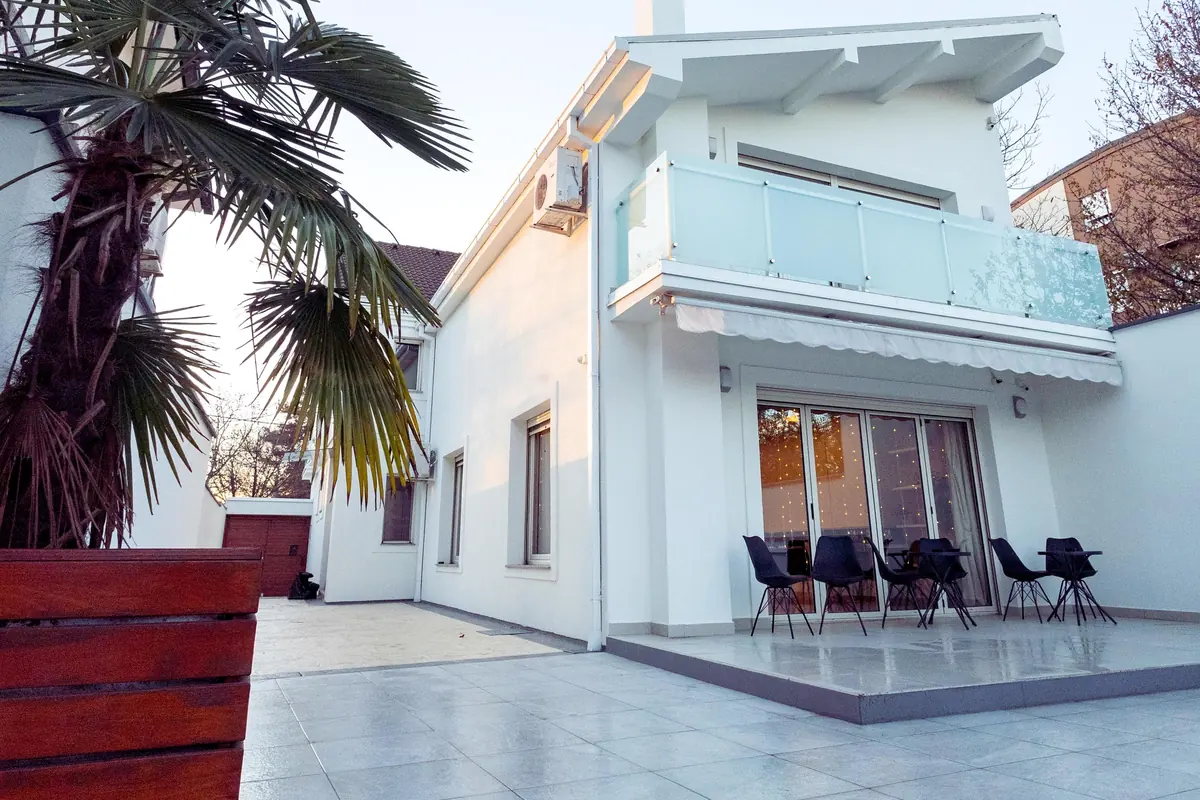 Casa Las Palmeras de fachada clara y ventanal oscuro